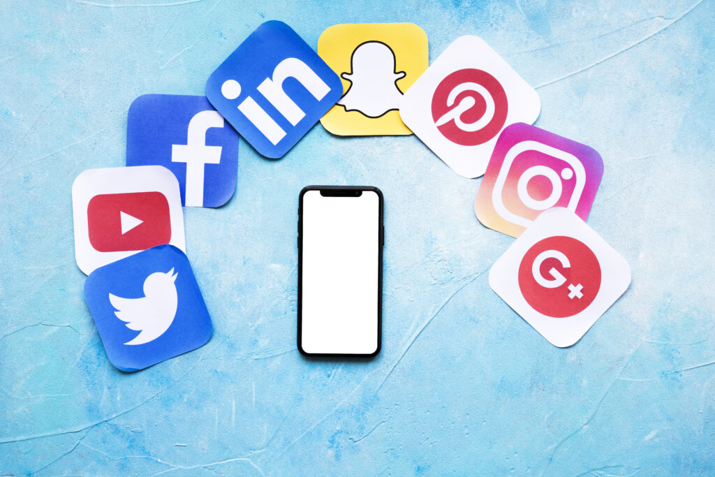 blank cellphone with various social networking paper icons blue backdrop